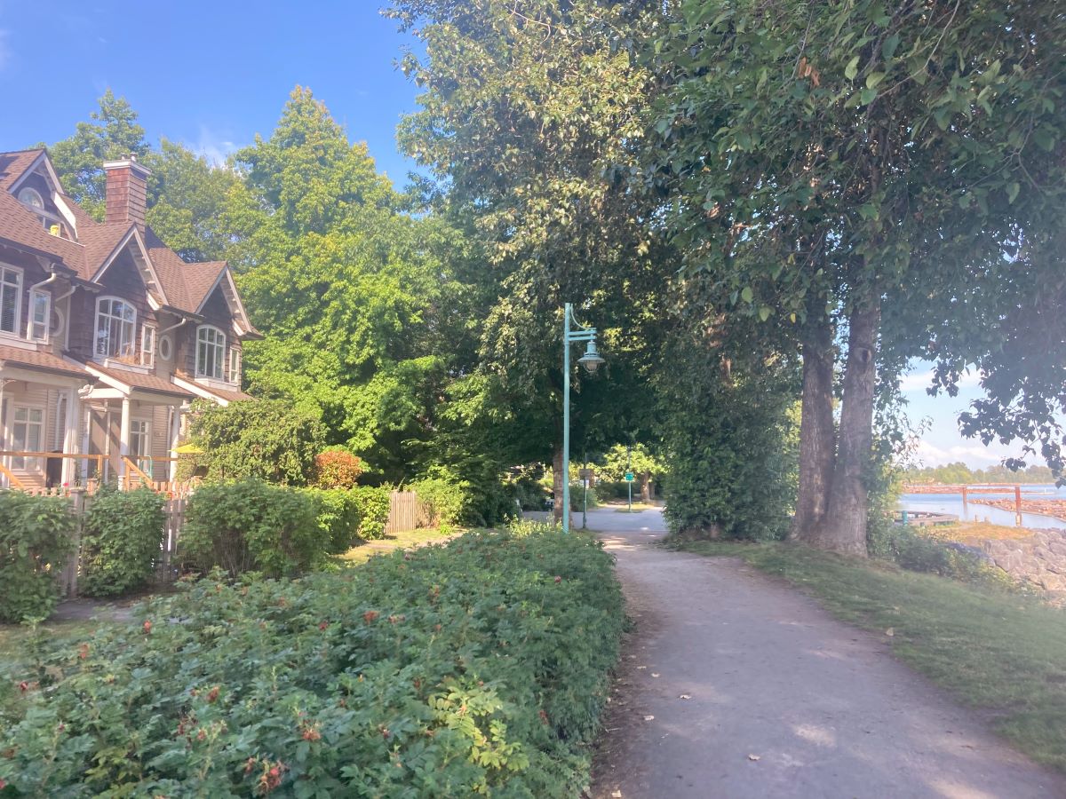 A path shaded by trees along a residential development. 